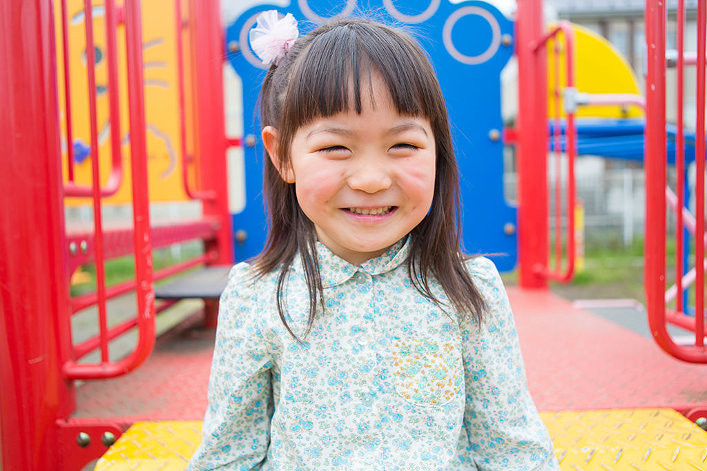 Smiling little girl in playground with background bokeh