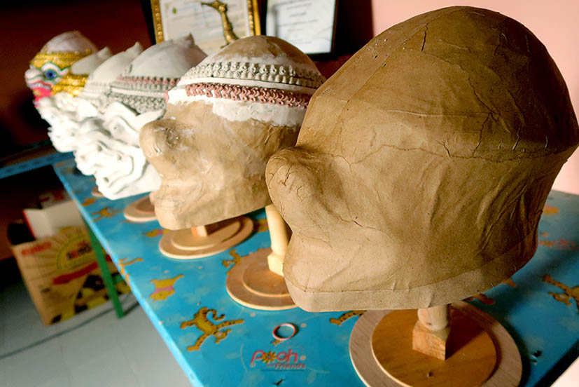 A row of Thai Khon masks at various stages of completion.