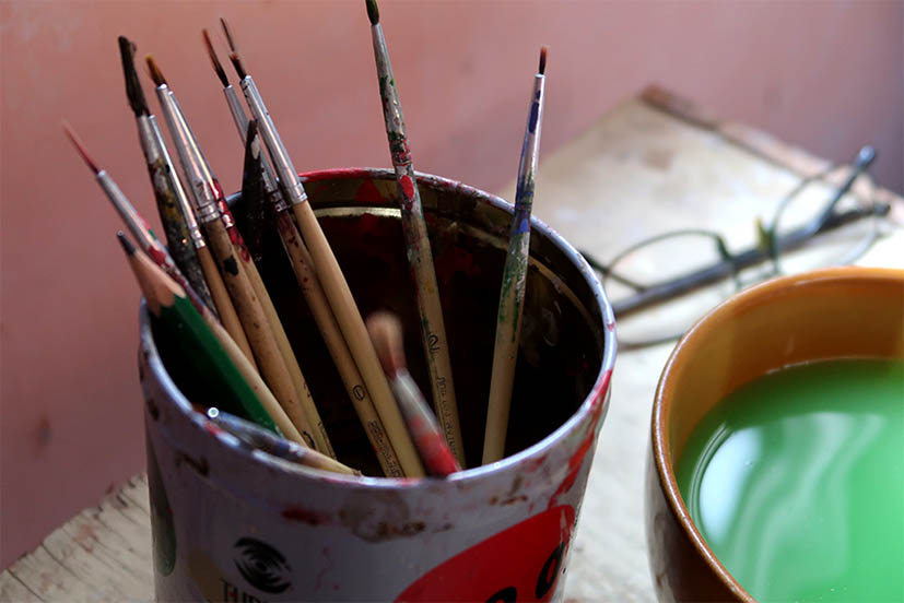 The brushes used in painting Thai Khon masks on Prateep Rodpai’s small work table.