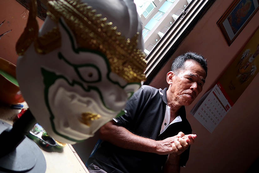 Prateep Rodpai talking about his craft with one of his masks slightly out of focus in the foreground.