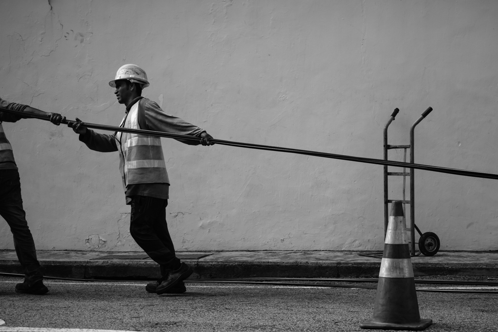 construction worker pulling cable black and white
