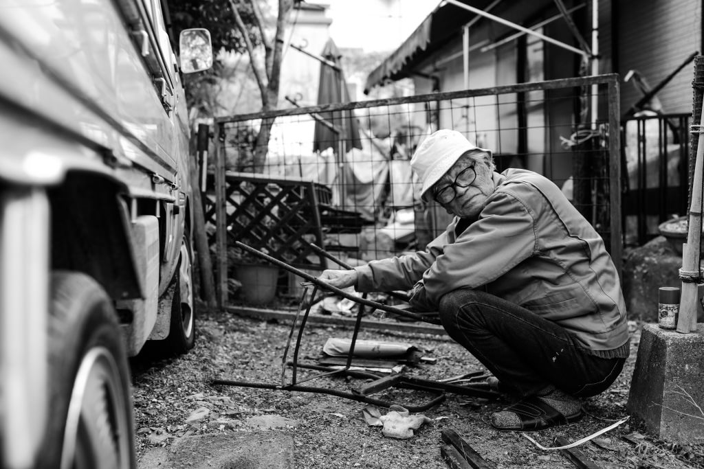 Black and white shot of man fixing chair