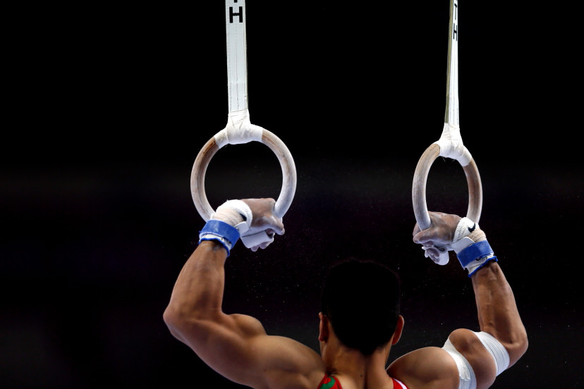 Male gymnast at rings event showcasing arm muscles