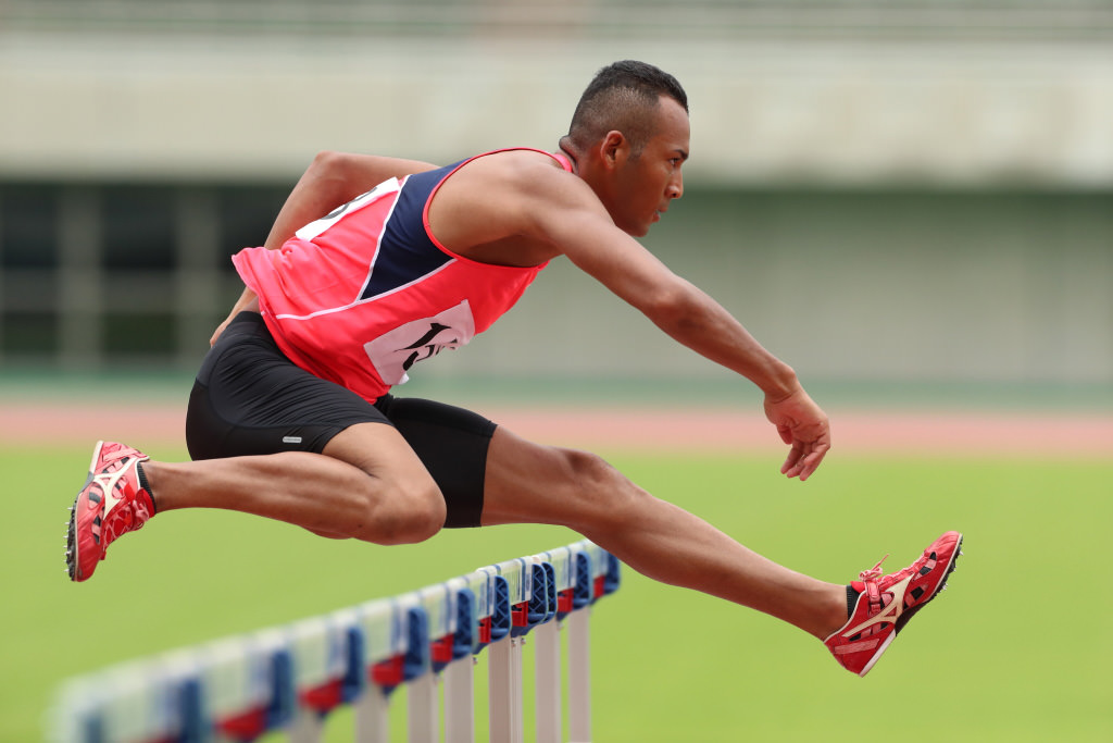 Athlete jumping over hurdle