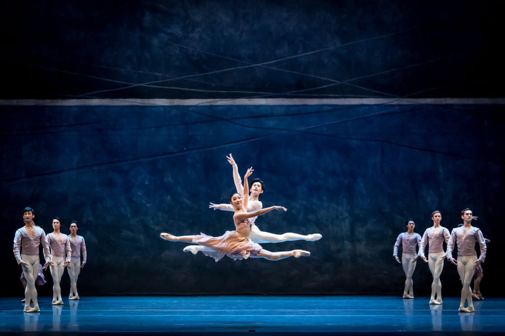 2 ballet dancers doing a grande jete in opposite directions