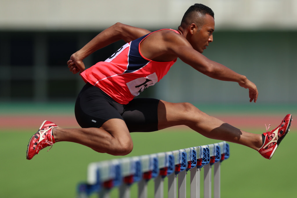 Athlete jumping over hurdle