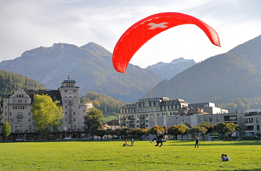 Red paraglider among buildings