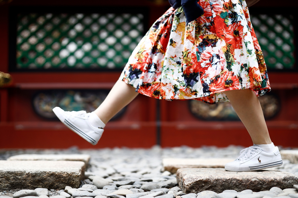 Feet of walking girl in flower print skirt