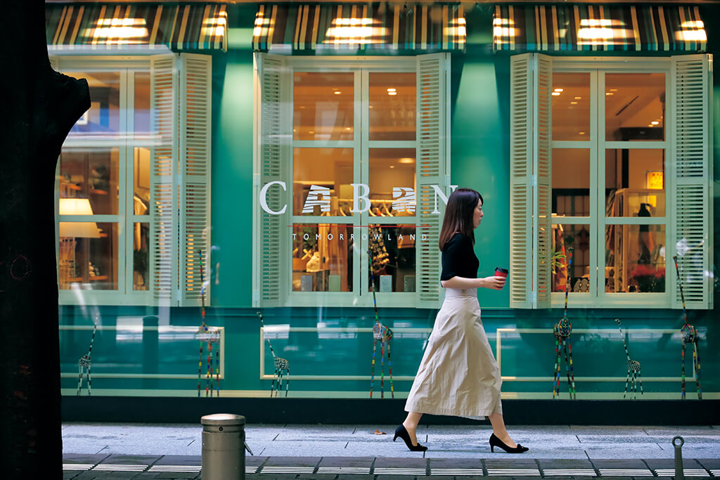 Lady walks past shops on the opposite side of the street