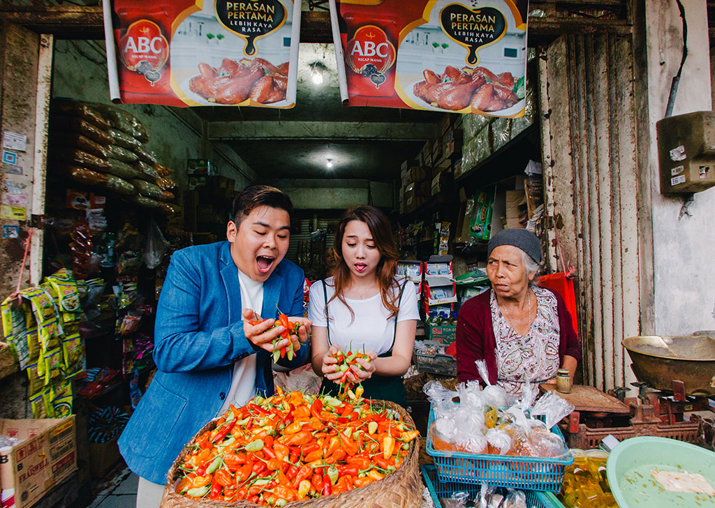 pre-wedding shoot couple in a Mom-and-Pop store holding chillies