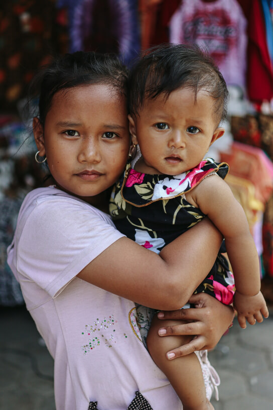 Girl carrying baby sister