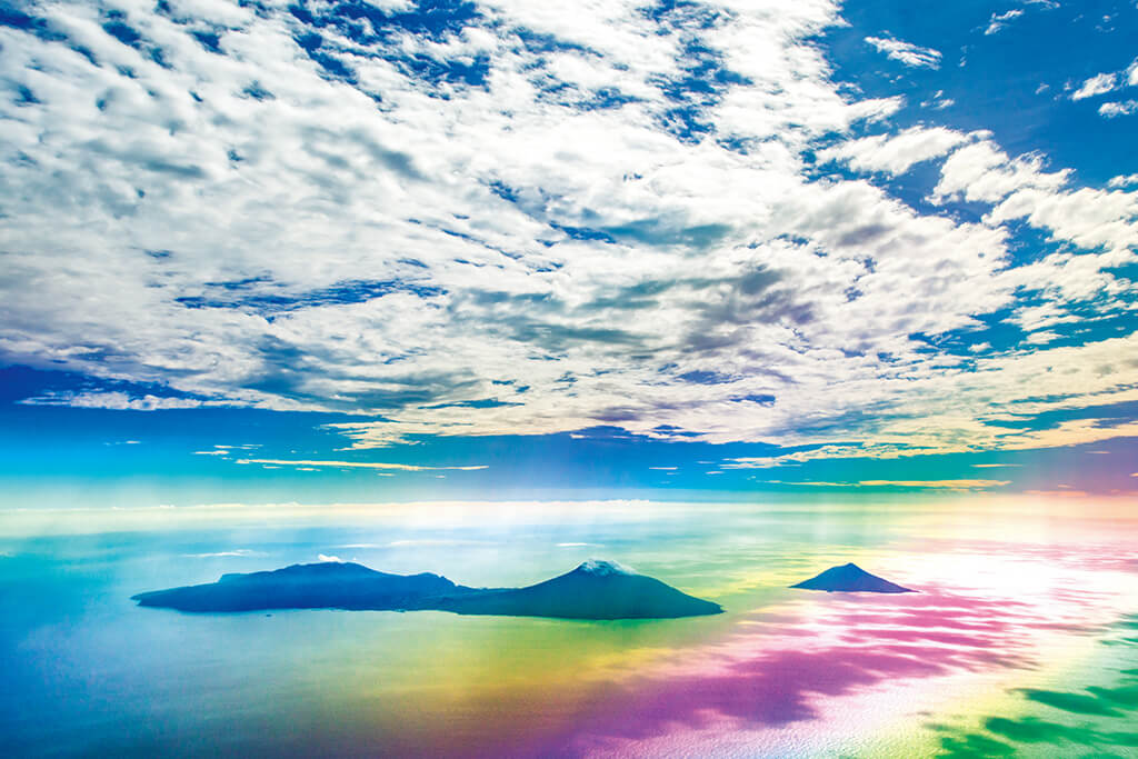 Rainbow-coloured island and clouds from high angle