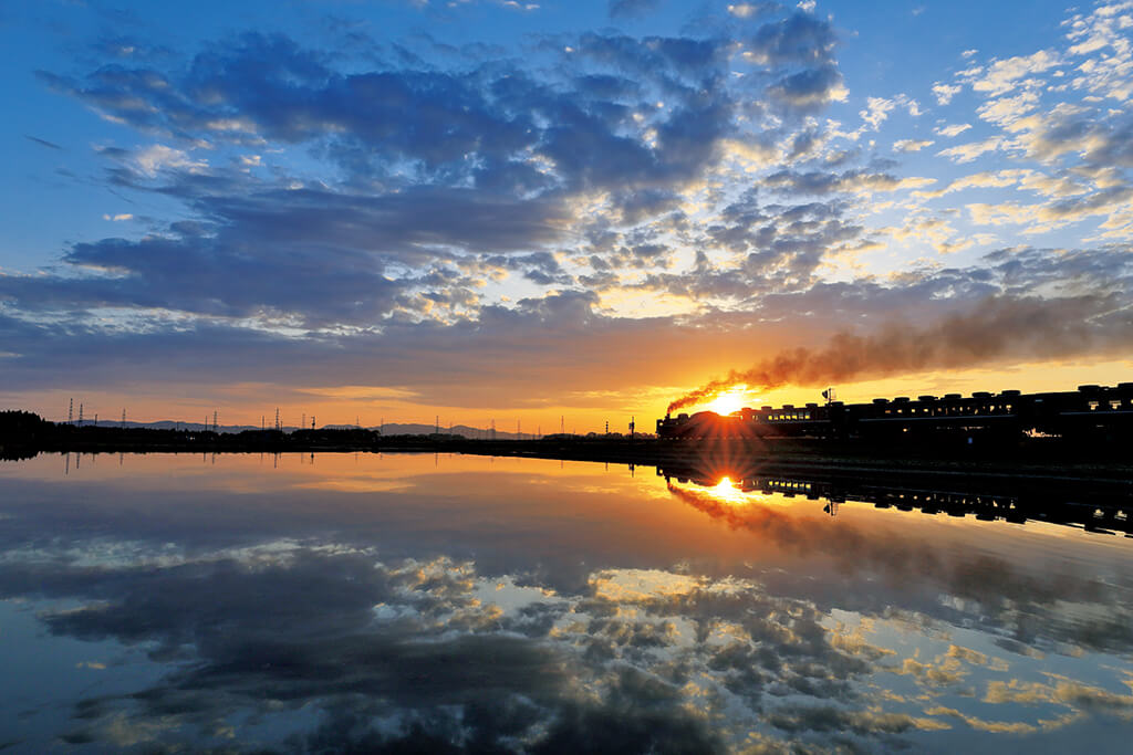 Steam train with water reflection with evening sun