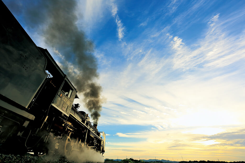 Close up of steam train moving towards the sun