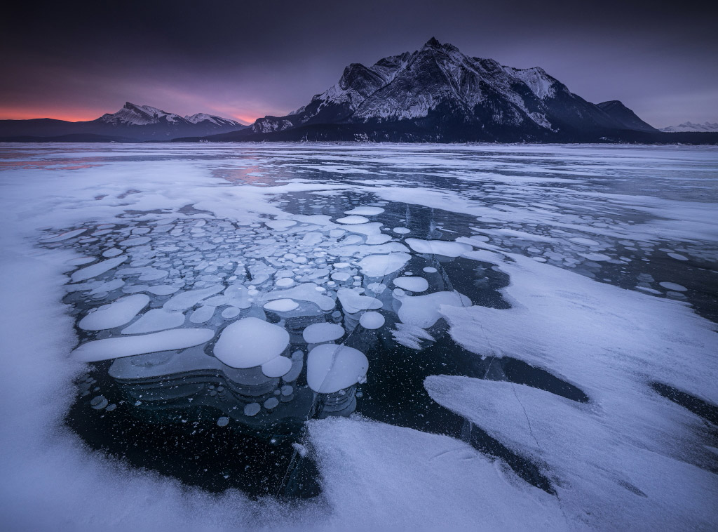 Frozen lake in front of Canadian Rocky mountains in low light