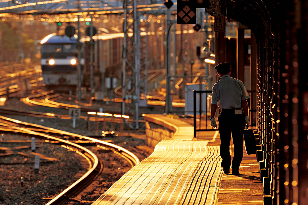 Man at end of open-air train station platform during golden hour
