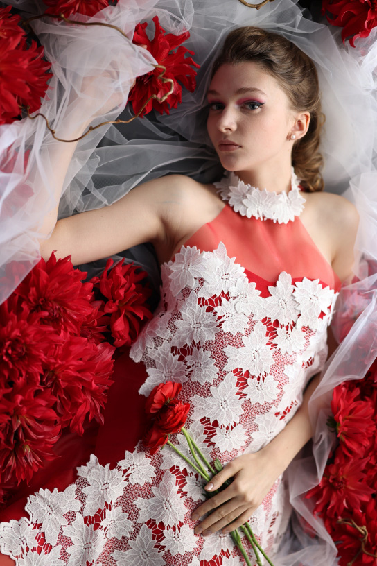 Model in red and white lying on red flowers