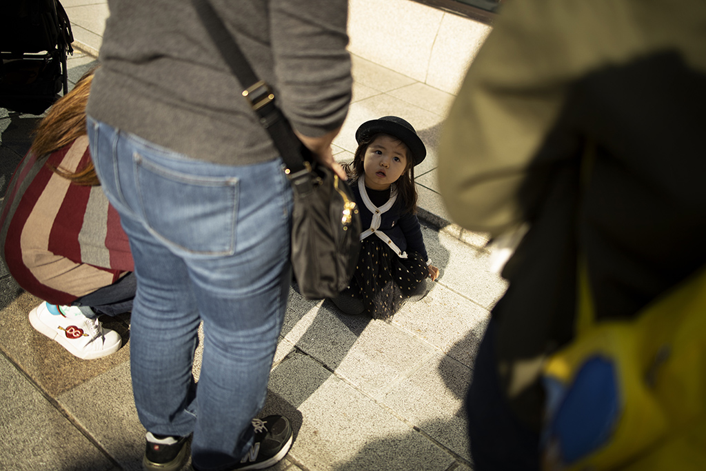 Little girl in street surrounded by adults